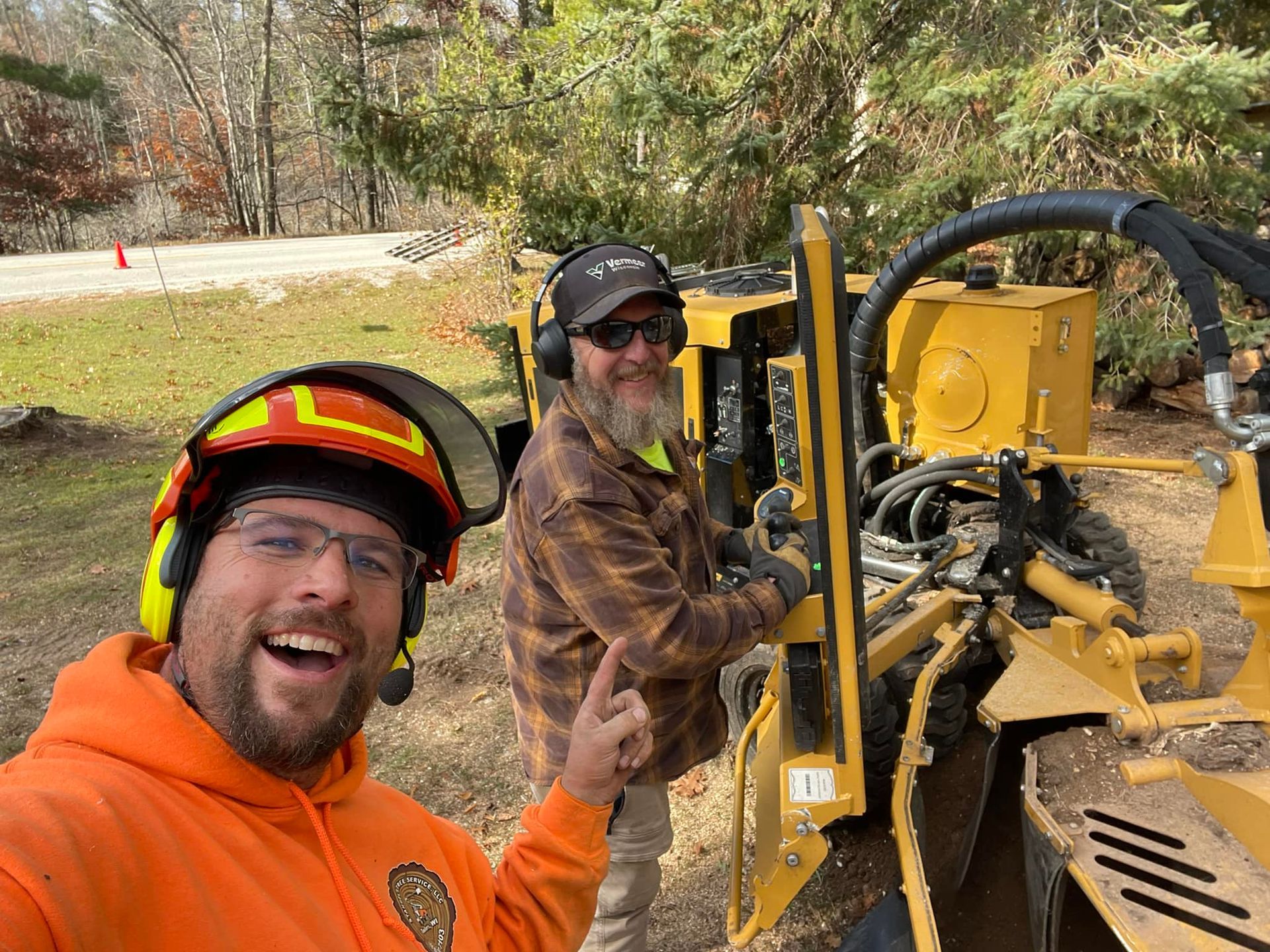 Two workers in safety gear posing beside a yellow bulldozer at a construction site