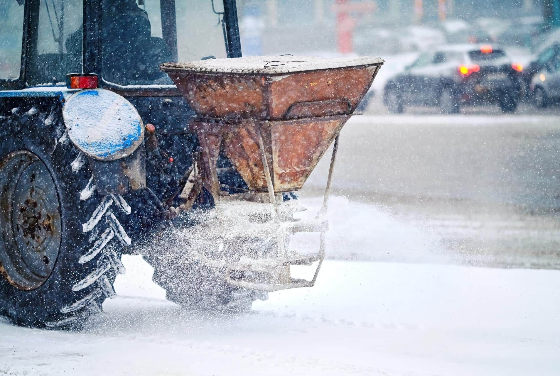 Snowplow truck spreading snow on a city street during a heavy snowfall