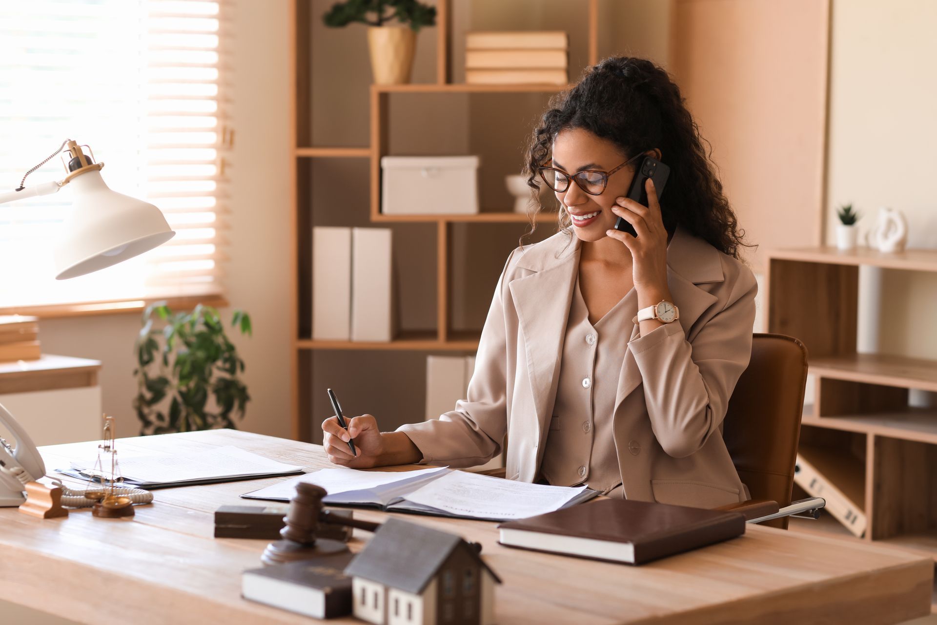 A woman is sitting at a desk talking on a cell phone.