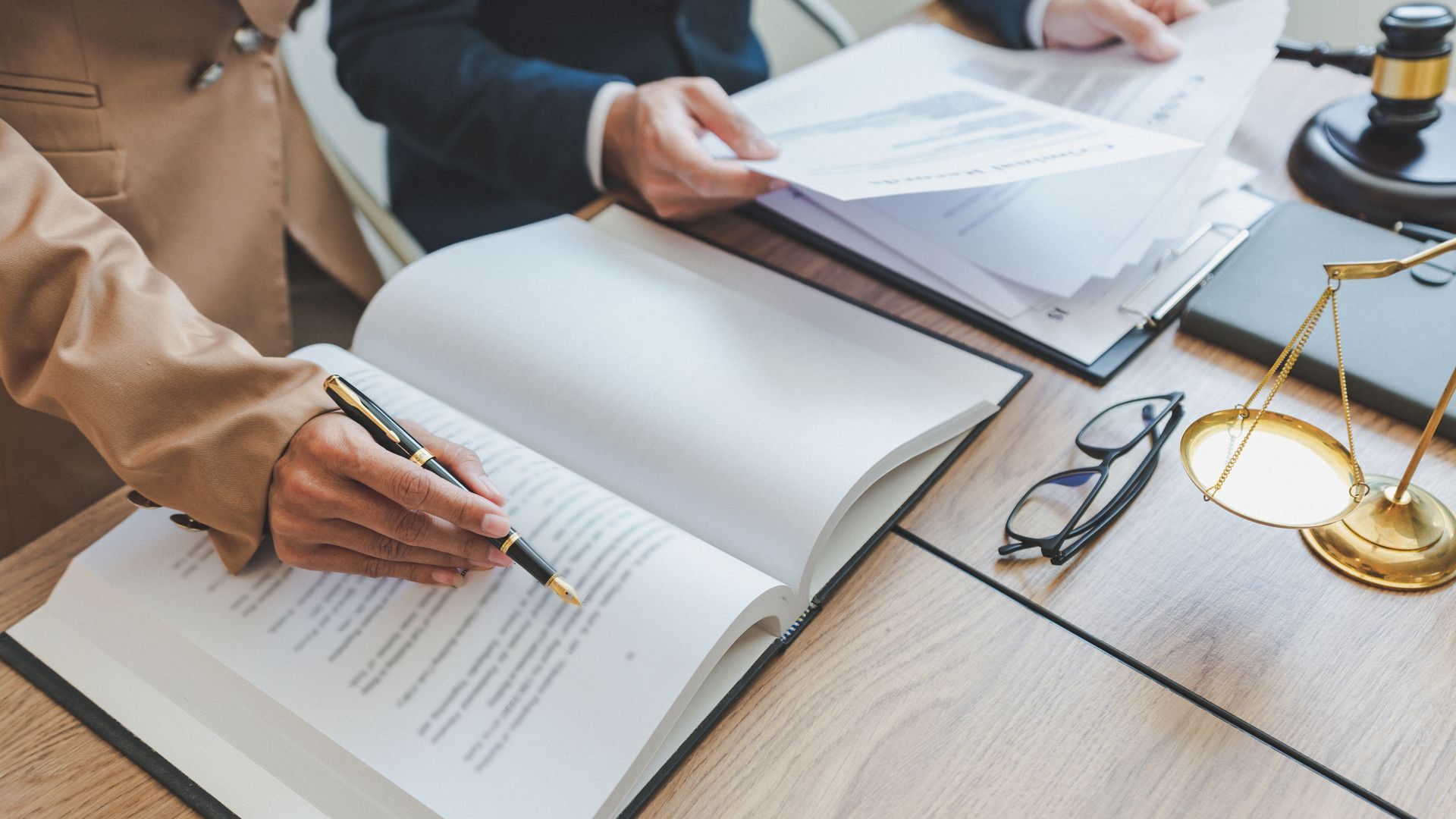A man and a woman are sitting at a table looking at papers and a book.