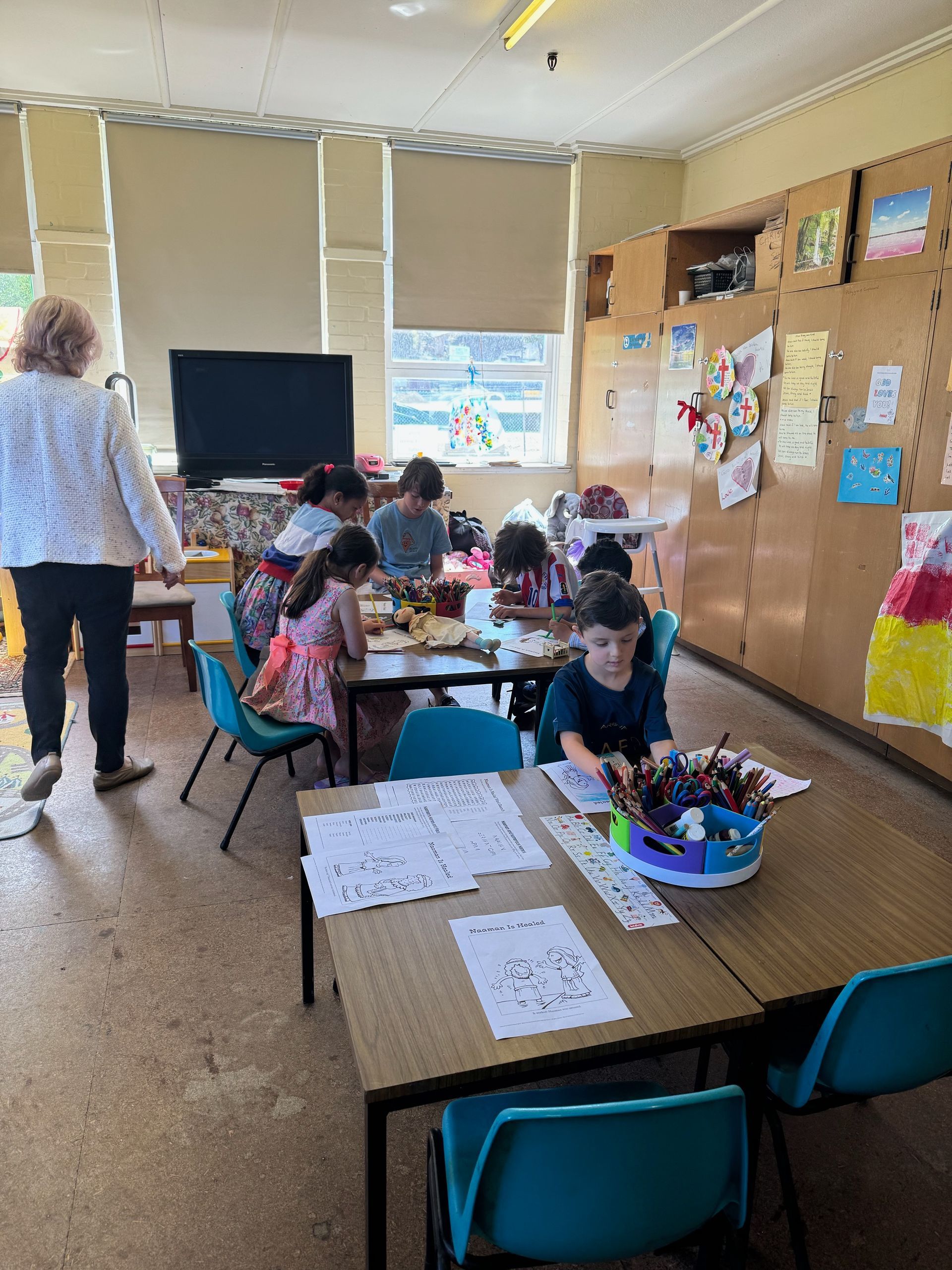 A group of children are sitting at tables in a classroom.