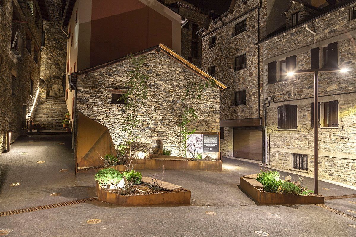 Un callejón estrecho entre dos edificios de piedra por la noche. Emfasi Estudi