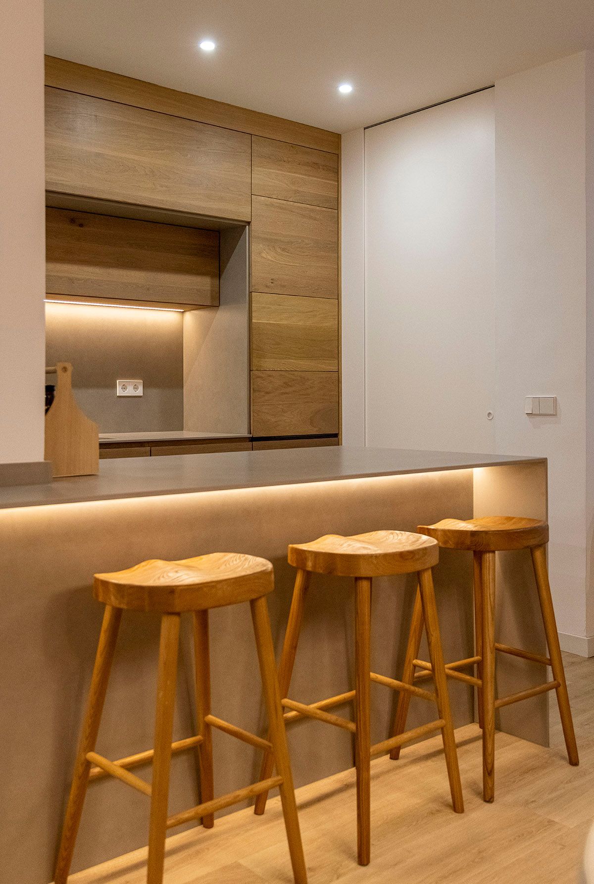 Tres taburetes de madera están colocados junto a un mostrador en una cocina. Fotografia Emfasi Estudi Andorra y Barcelona.