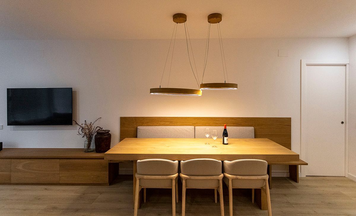 Una mesa de comedor con sillas y una botella de vino encima. Fotografía interiorismo. Fotografia Emfasi Estudi Andorra.