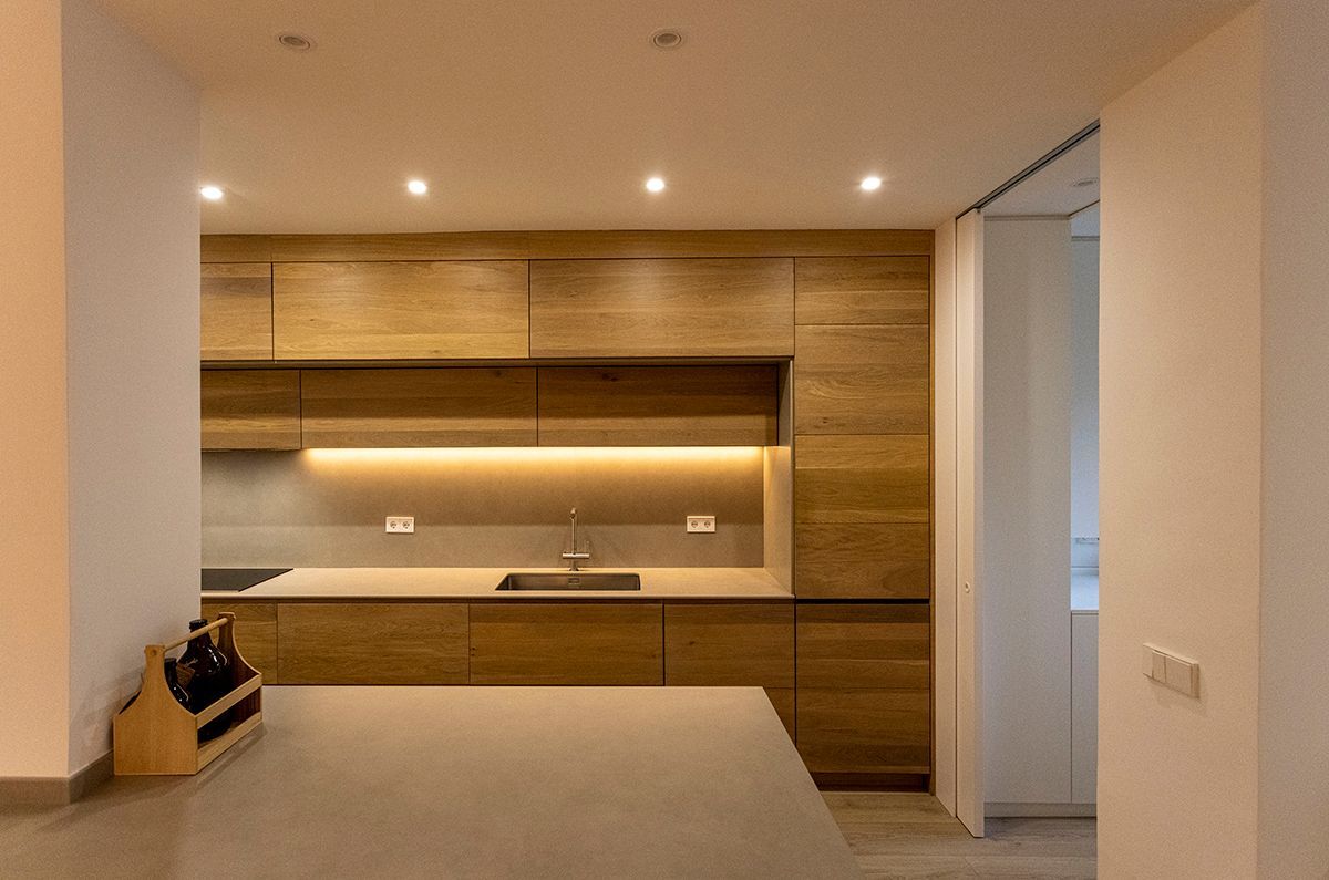 Fotografia Emfasi Estudi Andorra. Una cocina con muebles de madera y fregadero de acero inoxidable.