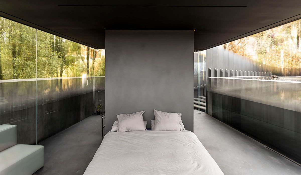 Hay una cama en medio de una habitación con muchas ventanas.