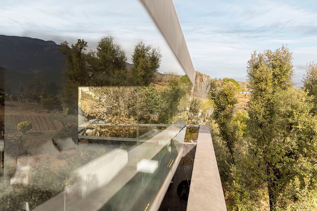 Un reflejo de árboles en una ventana de una casa. Fotografia Emfasi Estudi Andorra y Barcelona.