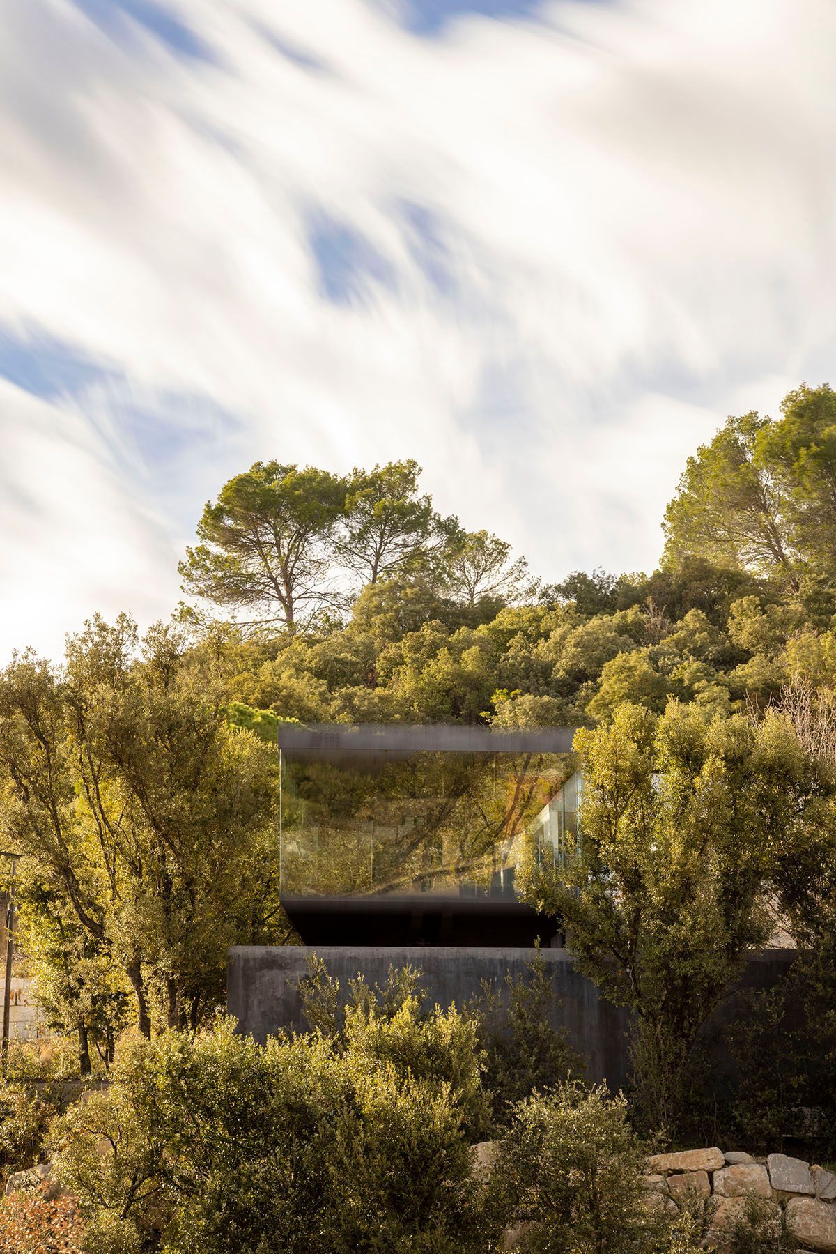 Fotografia Emfasi Estudi Andorra. Una casa está situada en la cima de una colina en medio de un bosque.