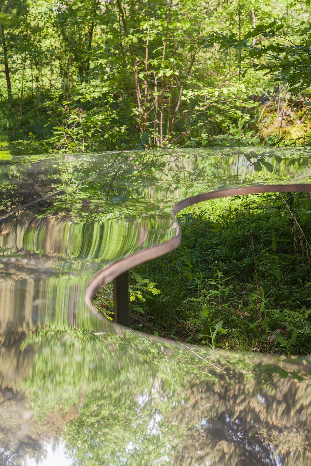 Hay un reflejo de árboles en una instalació0n artística. Fotografia Emfasi Estudi Andorra y Barcelona.