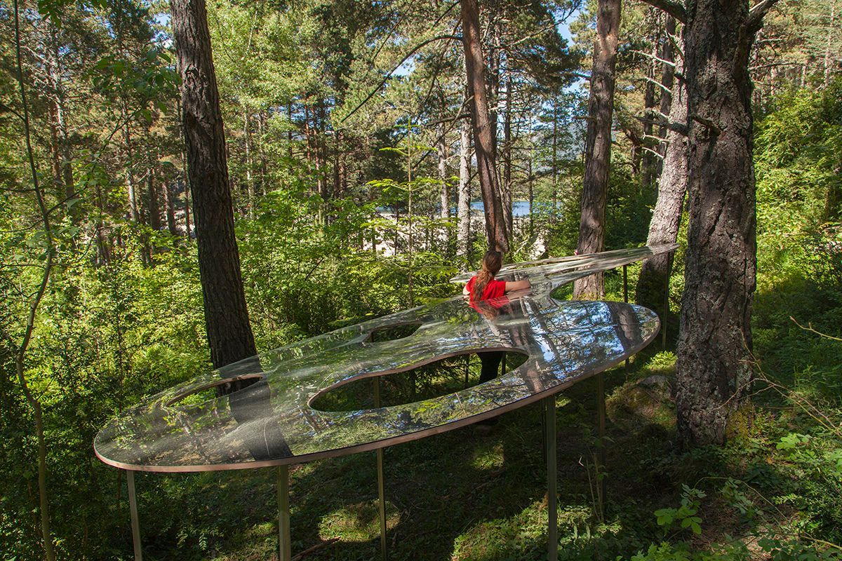 Fotografia Emfasi Estudi Andorra. Una gran mesa ovalada se encuentra en medio de un bosque.