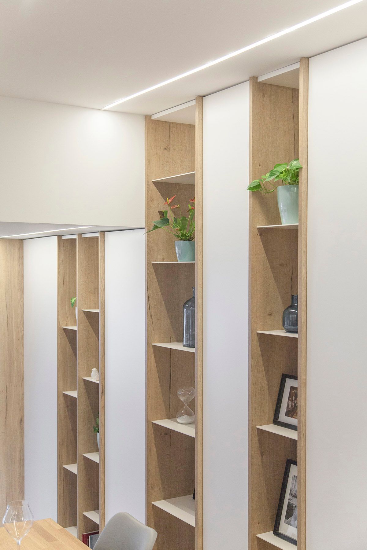 Un comedor con mesa, sillas y estanterías. Emfasi Estudi