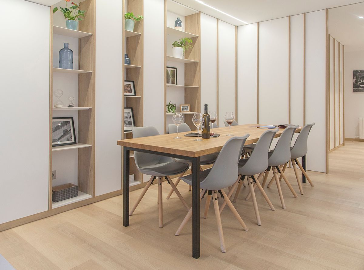 Un comedor con mesa y sillas y una botella de vino en la mesa. Emfasi Estudi