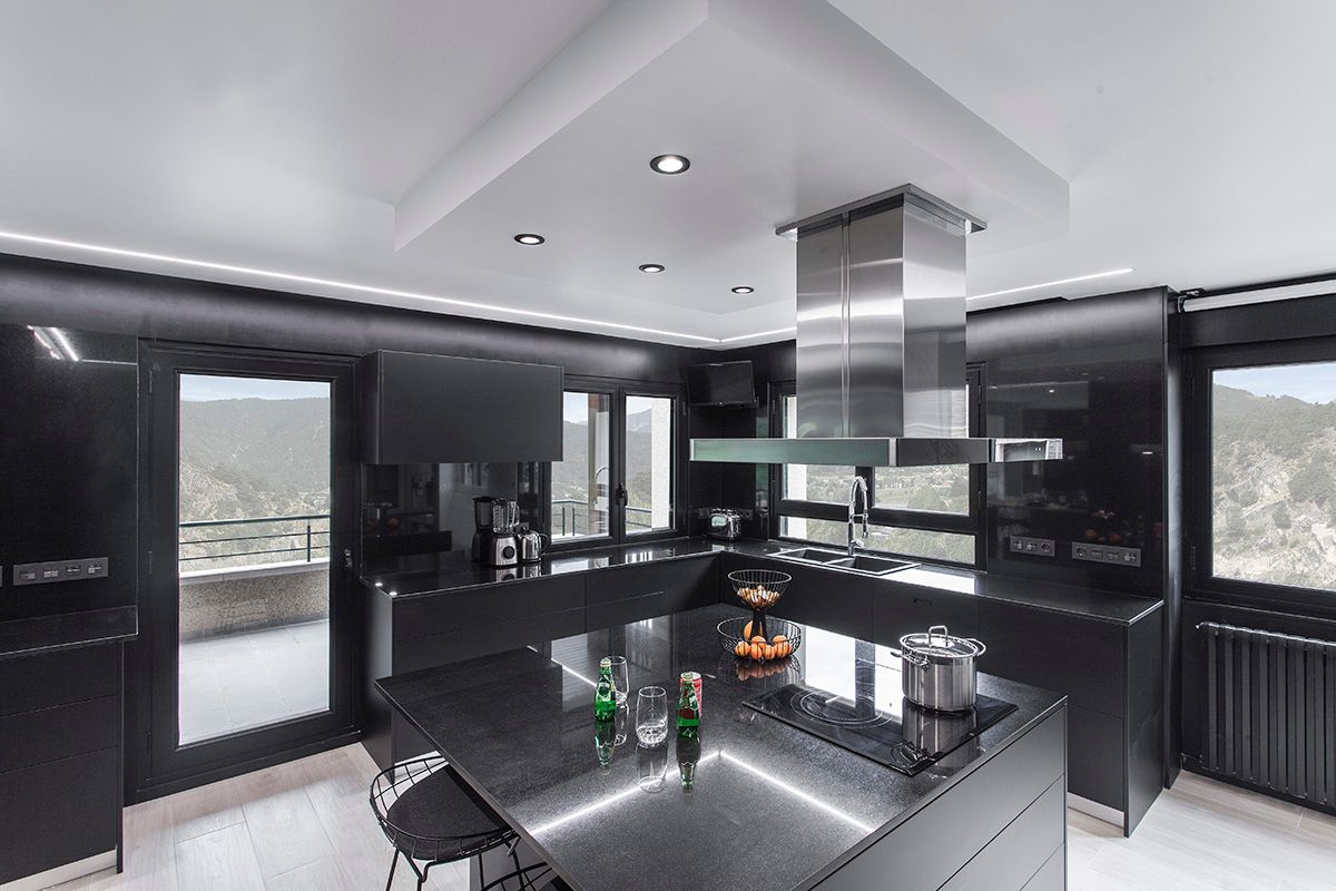 Una cocina con gabinetes negros y electrodomésticos de acero inoxidable. Fotografia Emfasi Estudi Andorra y Barcelona.
