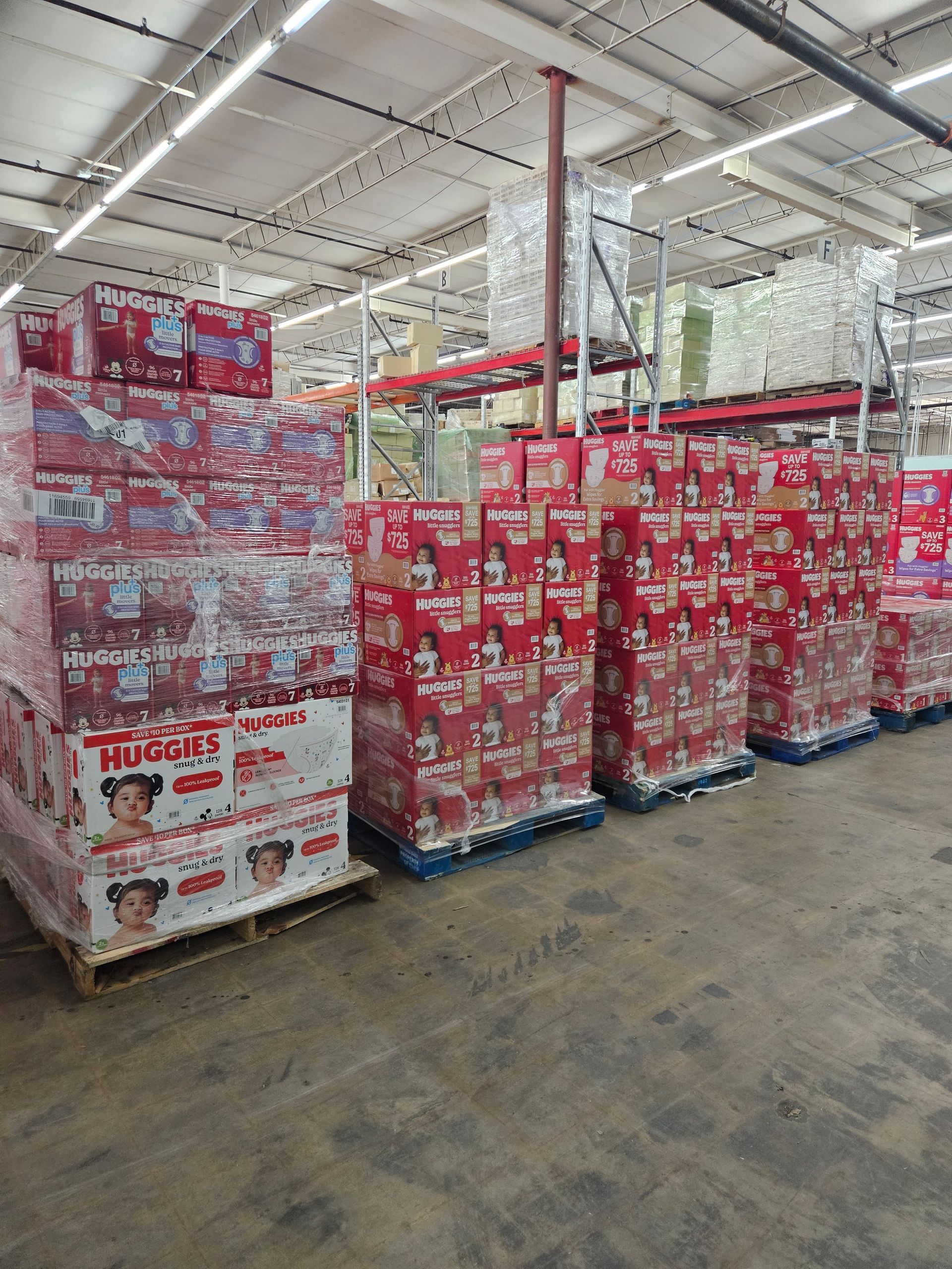 Warehouse aisle stacked with red and white drink cartons on pallets under bright industrial lighting