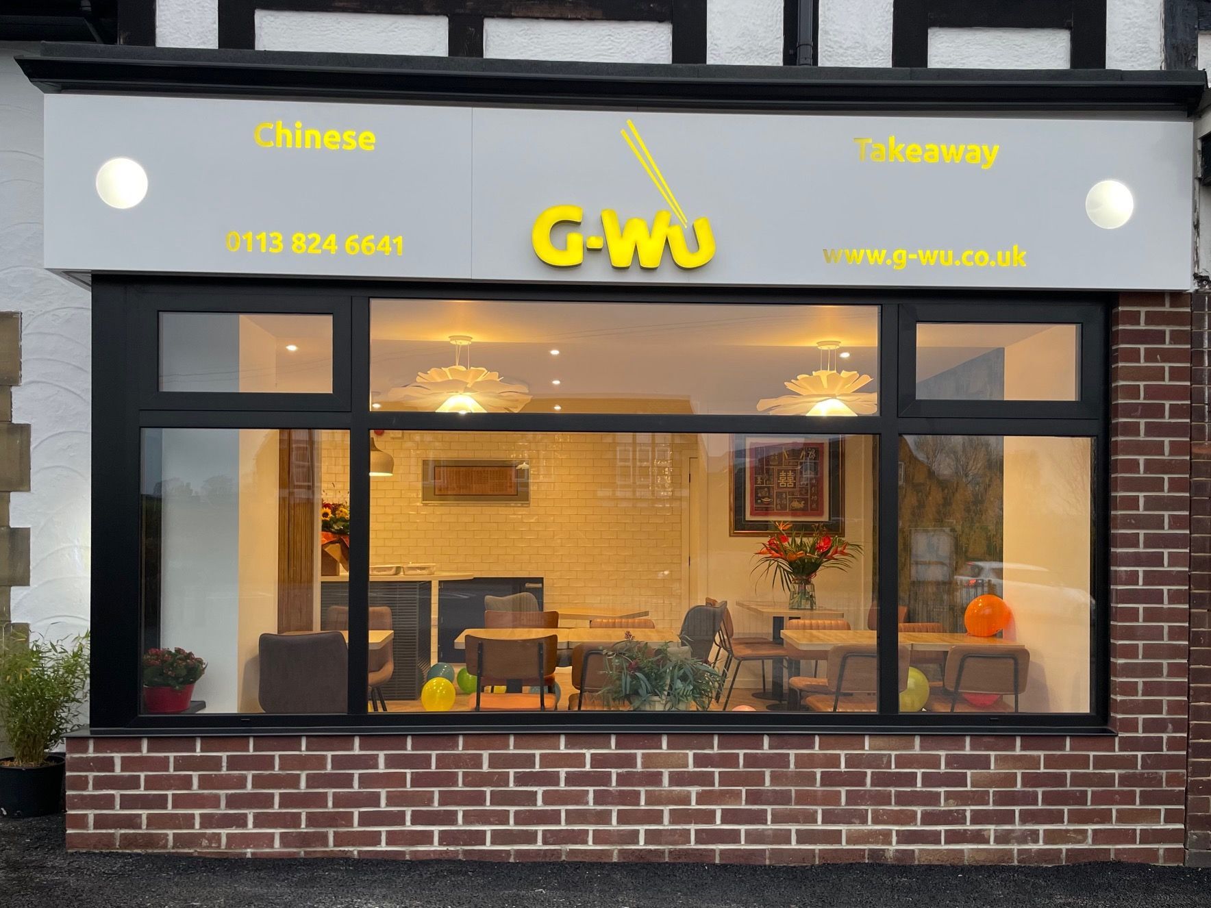 G-Wu Chinese takeaway storefront with window display; gray sign; brick facade.