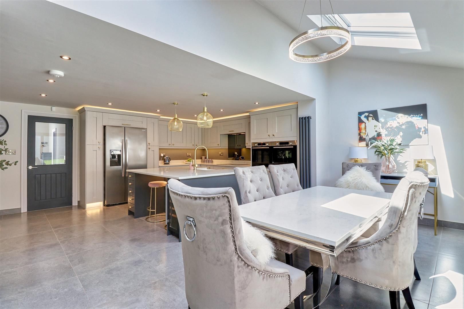 Open-plan kitchen and dining area with a dining table and chairs. Soft lighting and modern design.