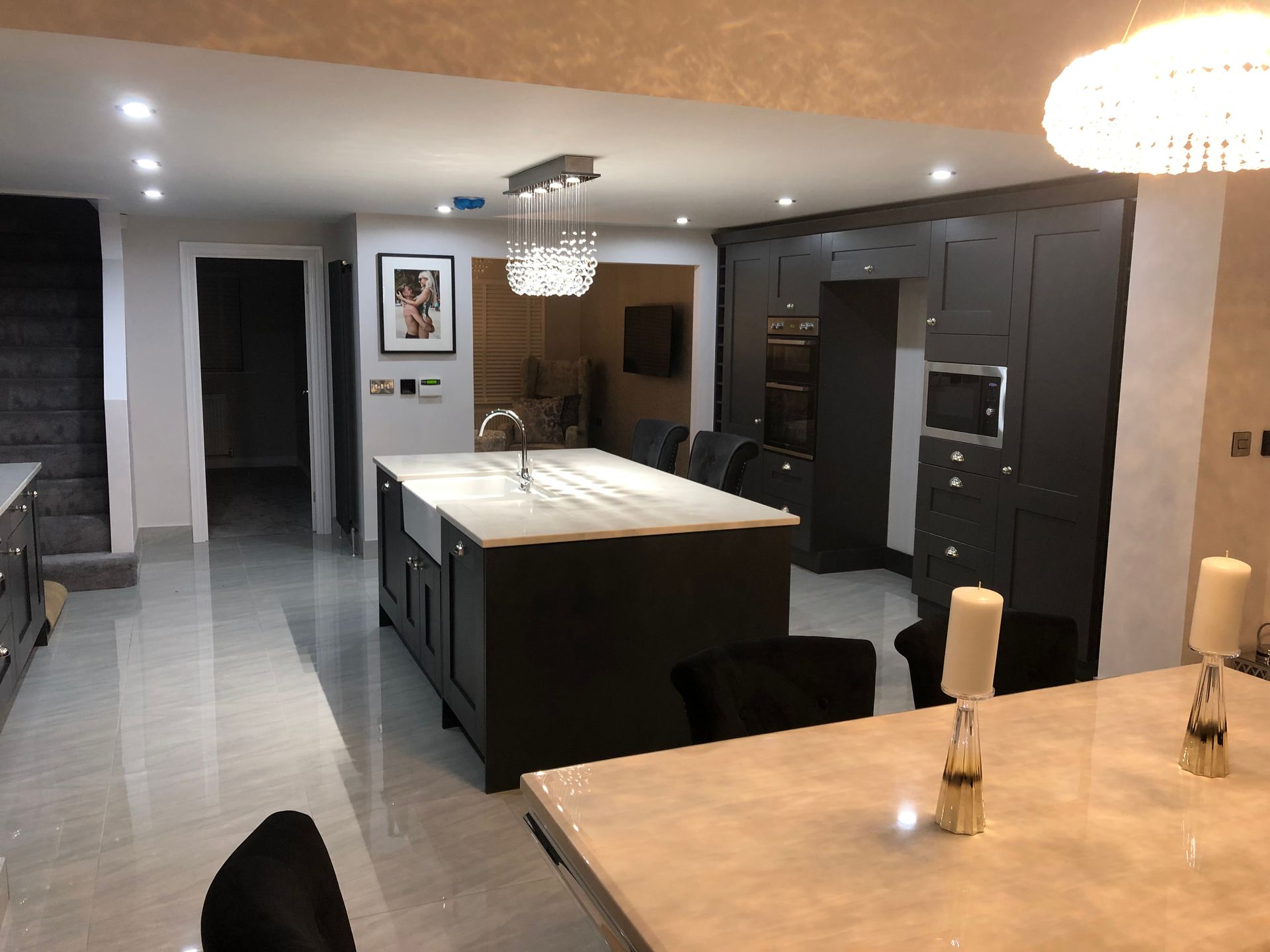 Modern kitchen with dark cabinets, large island, and a chandelier over the table.