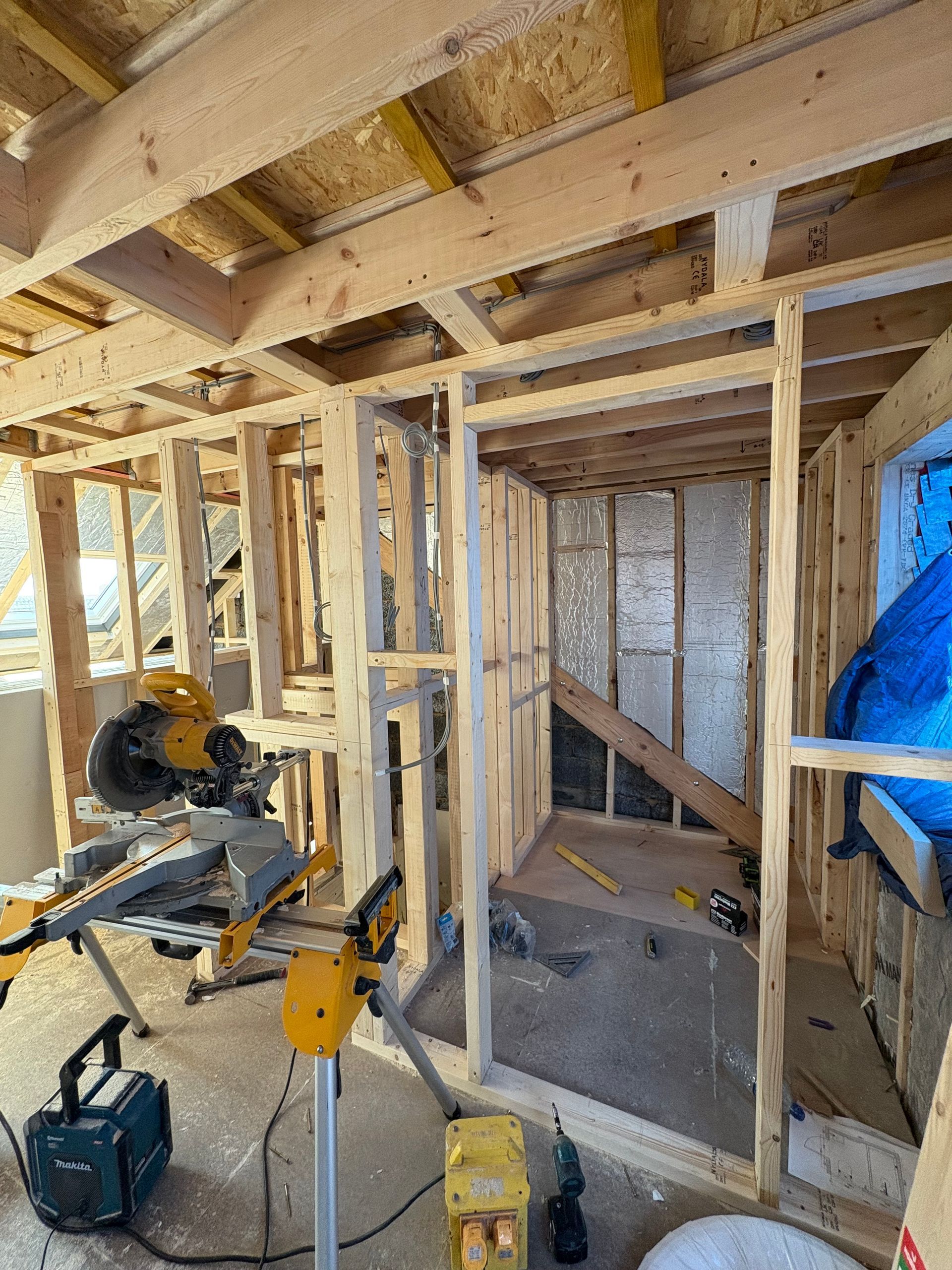 Interior view of a room under construction, with wooden frames and tools.