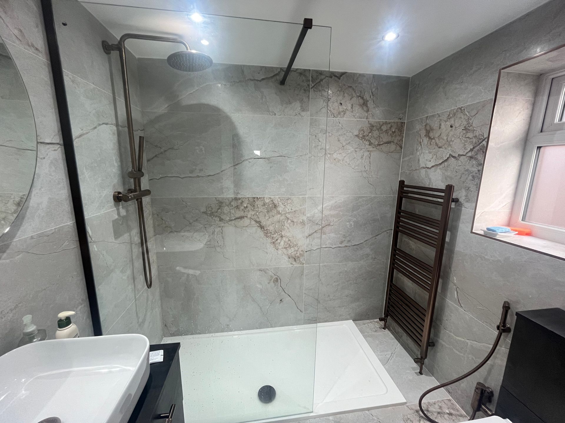 Modern bathroom with tiled walls, shower, towel rack, and sink.