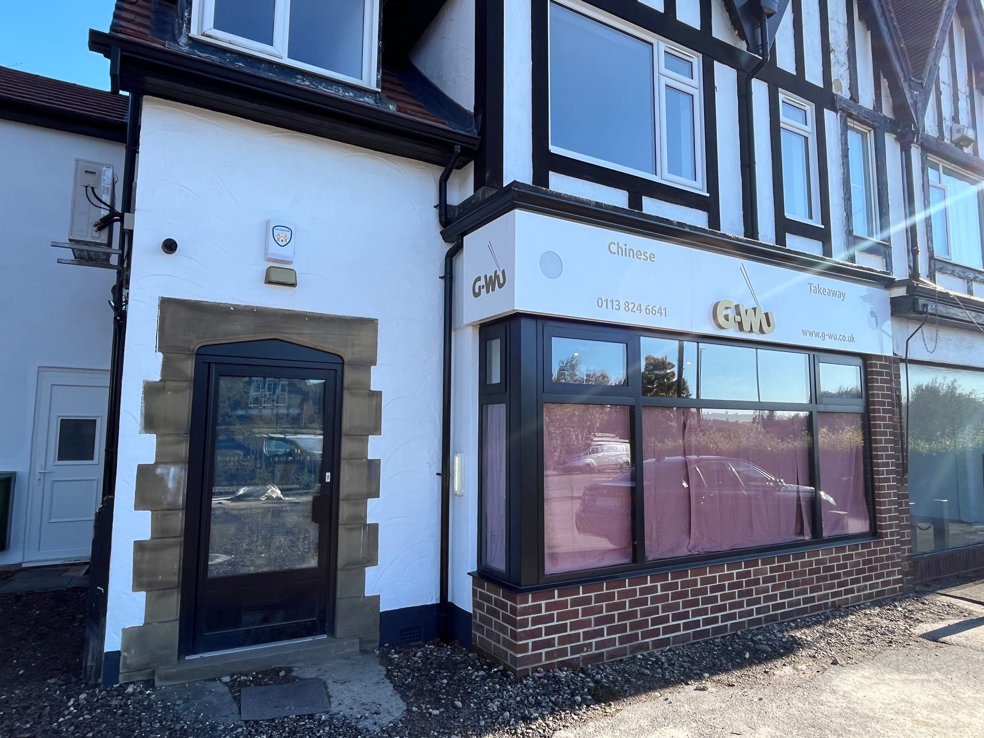 Exterior of a building with a black door, sign that says