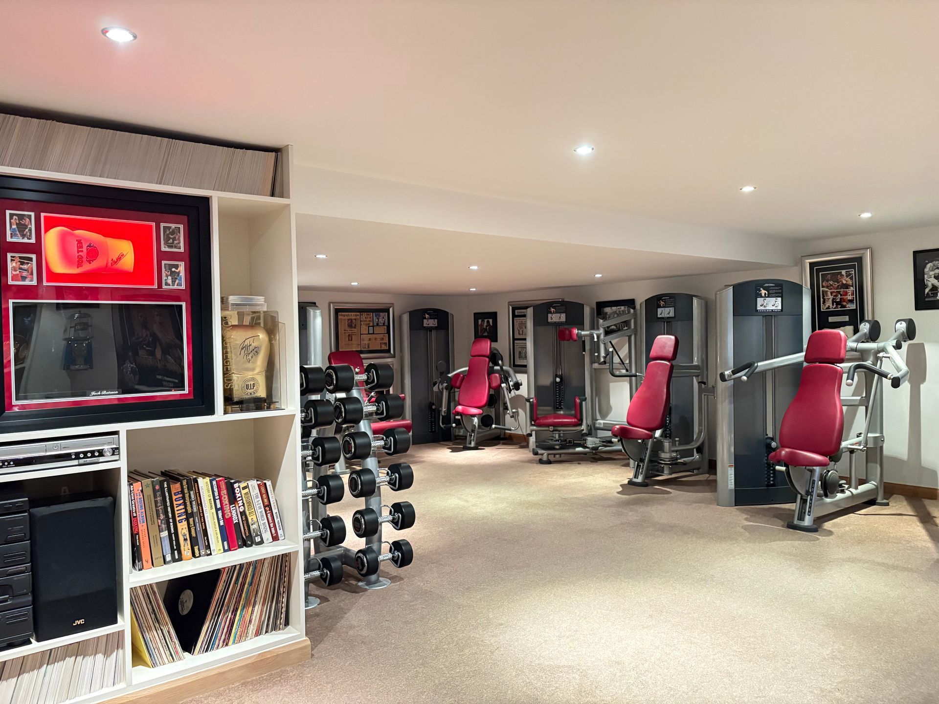 Home gym with weights, machines, and framed memorabilia on display.