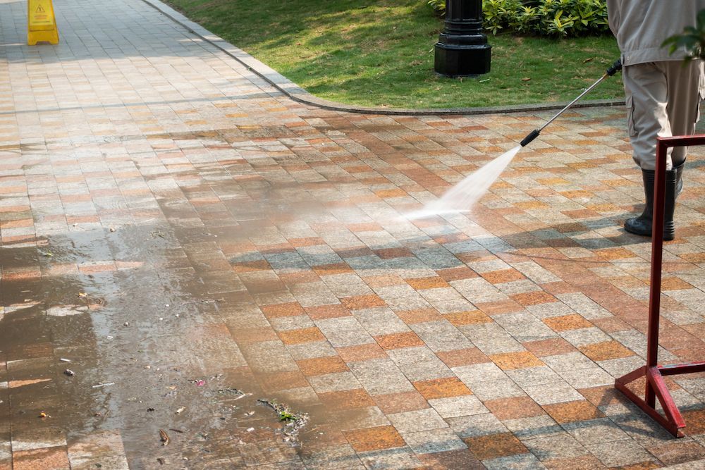 Person Power Washing a Brick Walkway Outdoors — Ausmade Services Pty Ltd in Norman Park, QLD