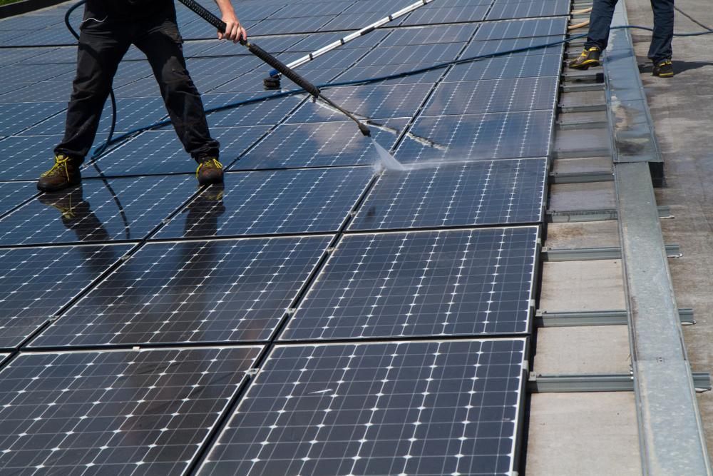 Two Men Are Cleaning Solar Panels on a Roof — Ausmade Services Pty Ltd in Chapel Hill, QLD