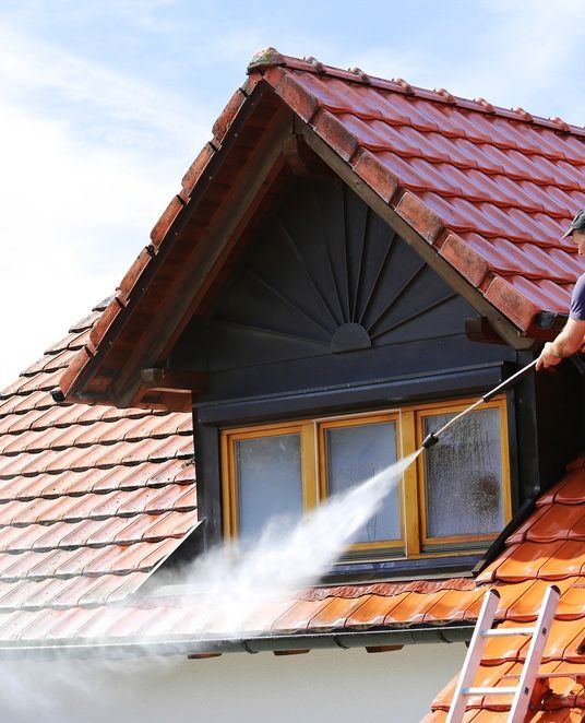 Man Pressure Washes Red Roof — Ausmade Services Pty Ltd in Camp Hill, QLD
