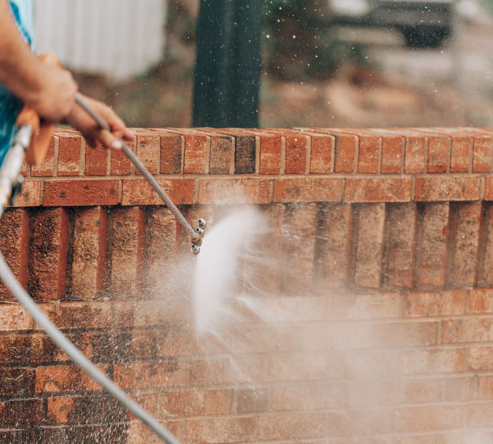 Person Power Washing a Brick Wall — Ausmade Services Pty Ltd in Coorparoo, QLD