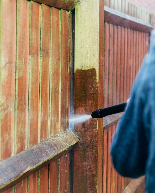 Person Pressure-washing a Weathered Wooden Fence Panel — Ausmade Services Pty Ltd in Chapel Hill, QLD