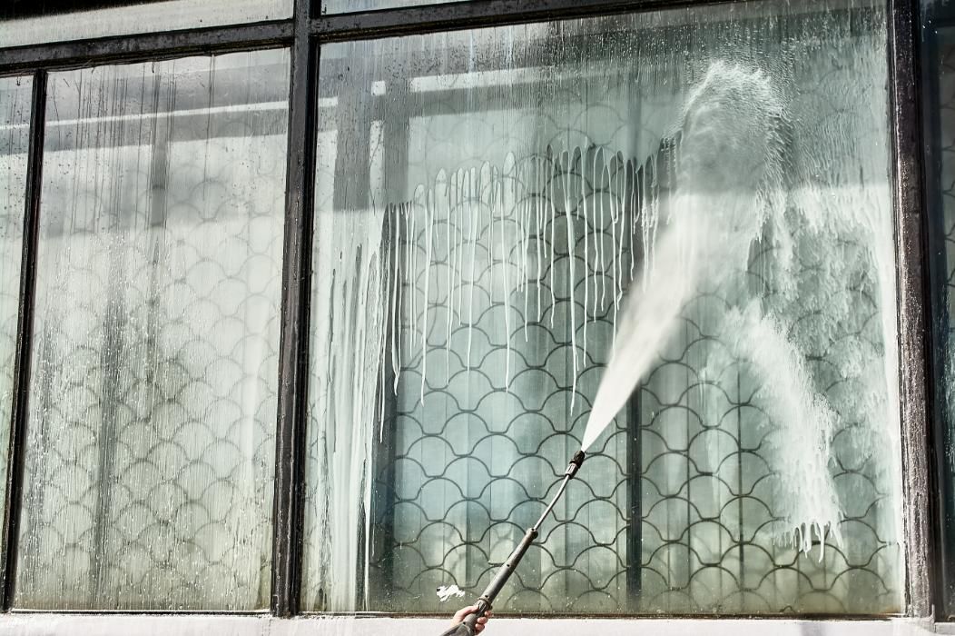 Person is Cleaning a Window With a High Pressure Washer — Ausmade Services Pty Ltd in Coorparoo, QLD