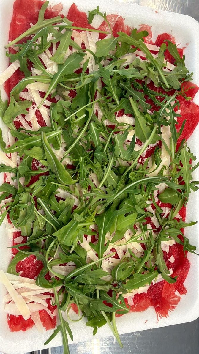 Piatto bianco di insalata guarnito con rucola, formaggio sbriciolato e pezzi di barbabietola rossa.