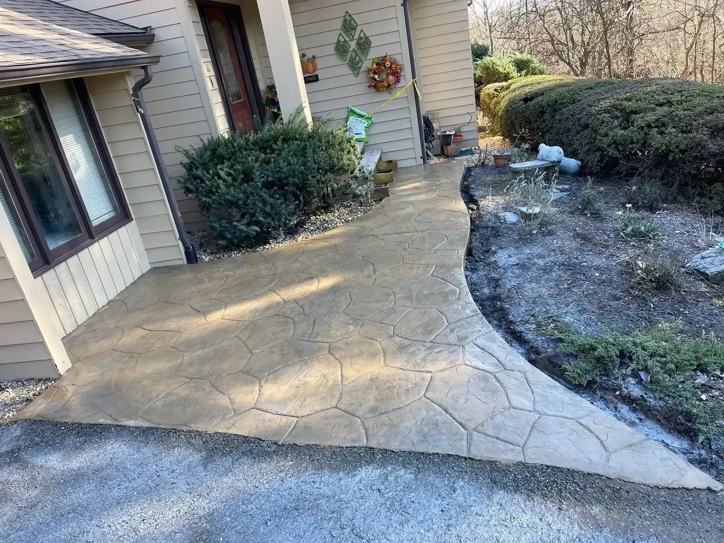 Brick house porch with bright yellow door and a newly paved stone walkway beside landscaping