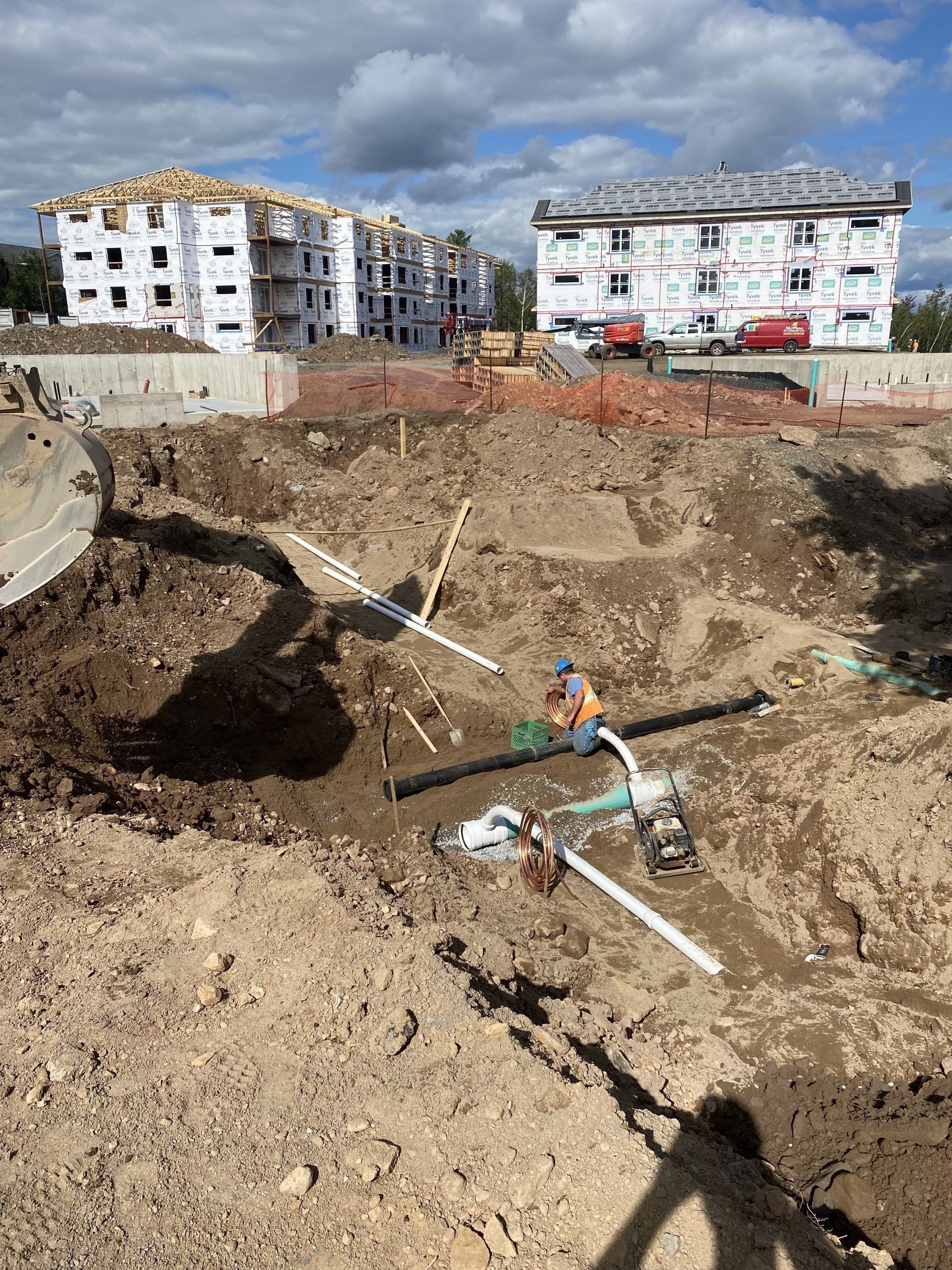 A construction site with a lot of dirt and buildings in the background.