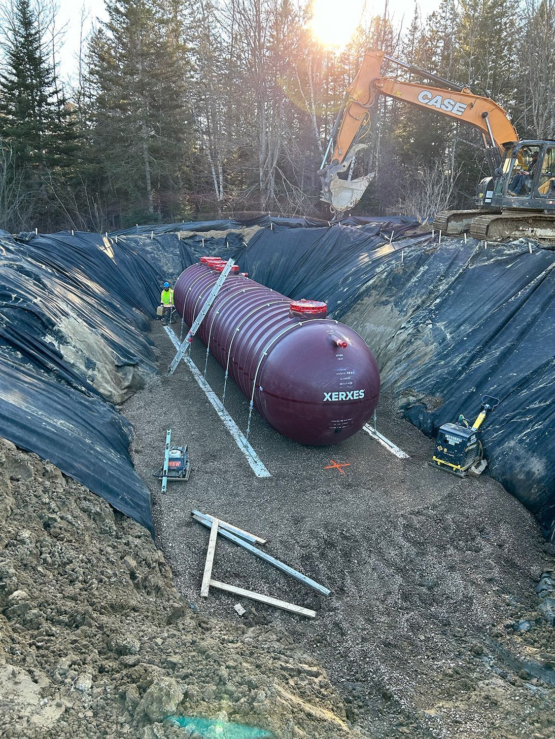 A large purple tank is sitting in the middle of a dirt field.
