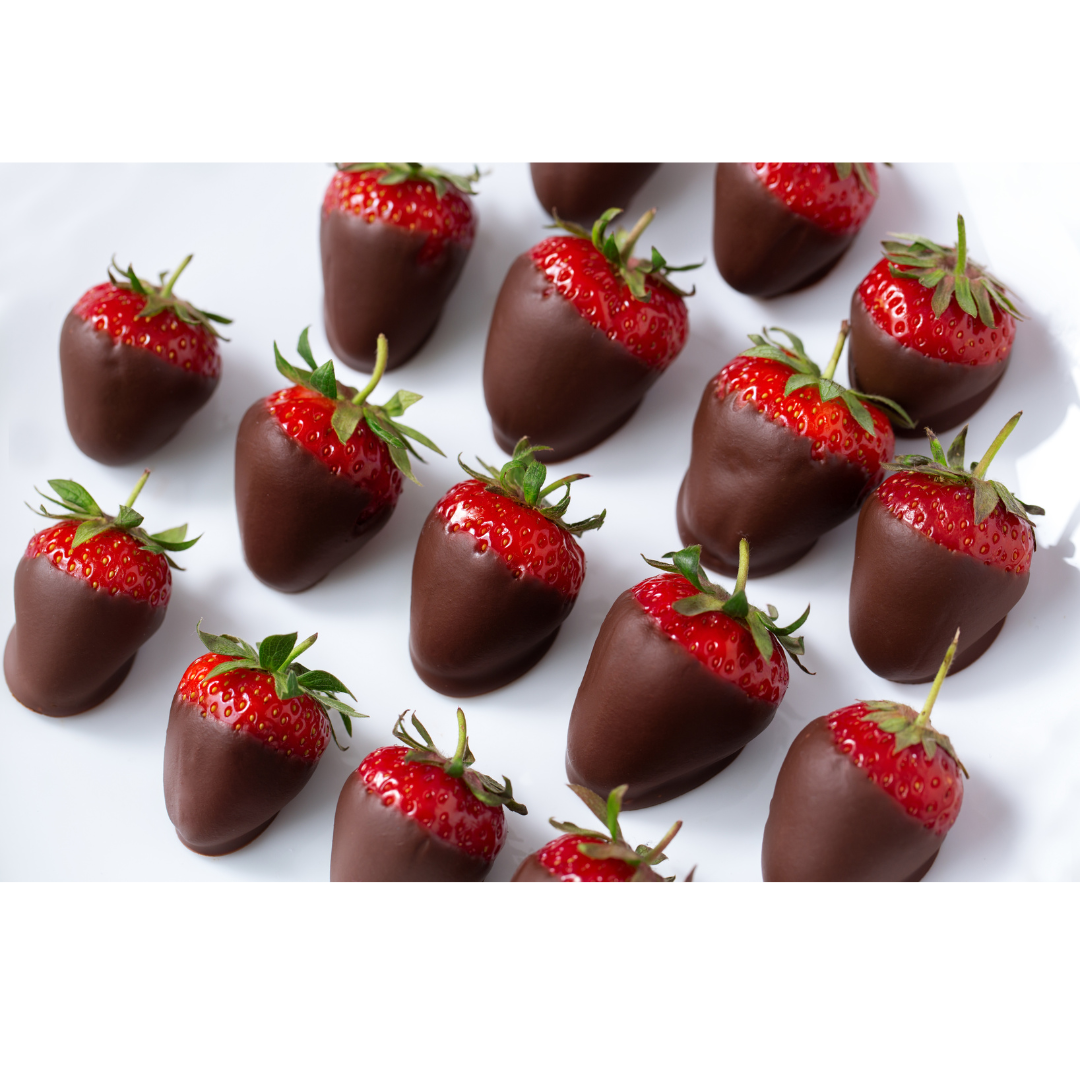 A top-down view of several fresh strawberries partially dipped in smooth, dark chocolate on a plain white background.
