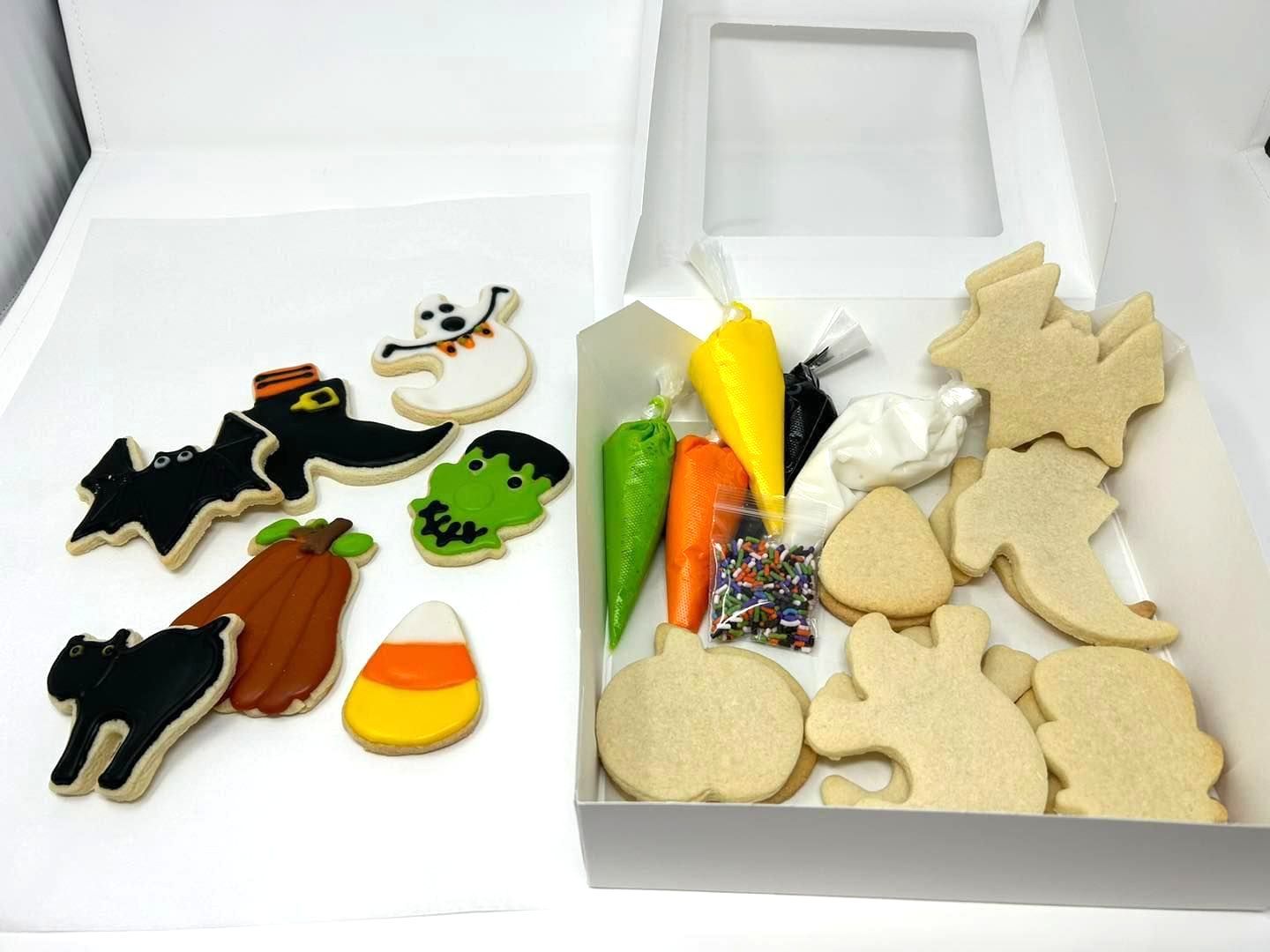 A Halloween DIY cookie decorating kit with finished cookies next to a box containing plain cookies, icing, and sprinkles.