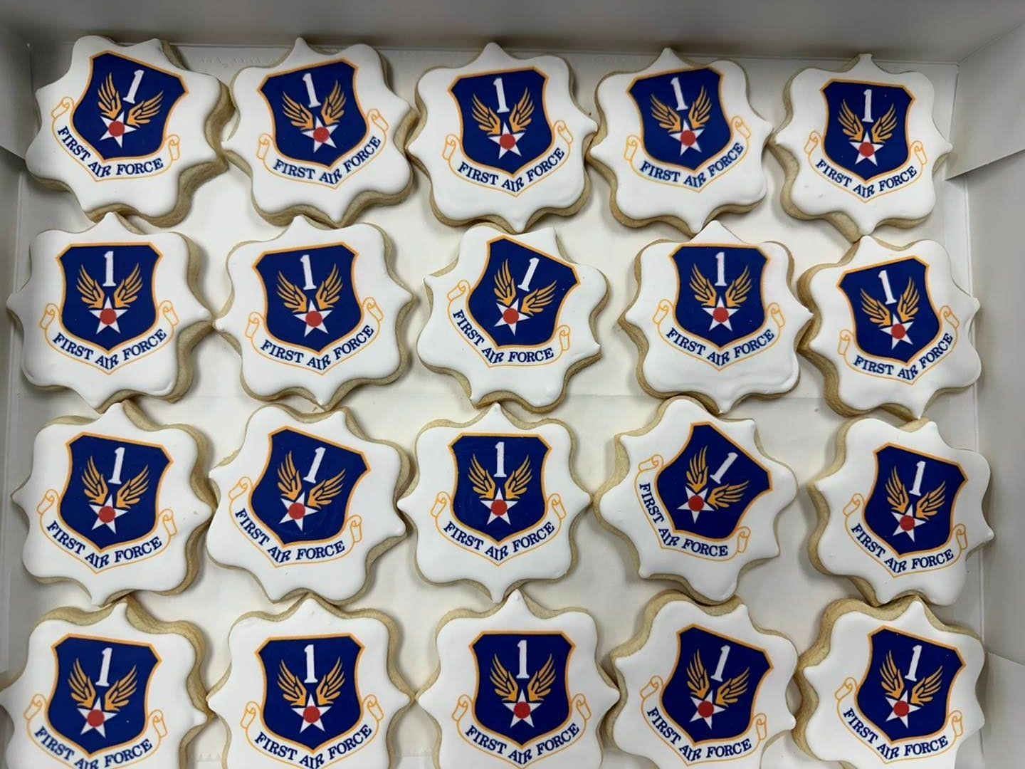 A box filled with 20 star-shaped sugar cookies, each decorated with the First Air Force emblem on a blue shield.
