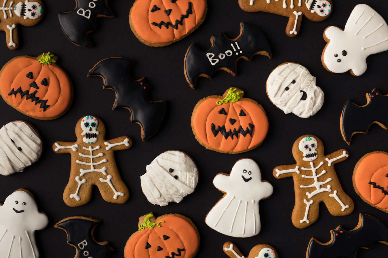A festive assortment of Halloween-themed sugar cookies, including pumpkins, bats, ghosts, mummies, and skeletons.