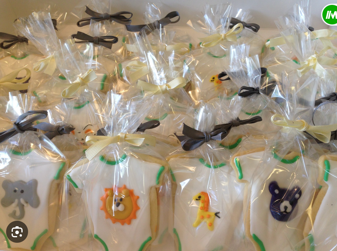 Onesie-shaped cookies with animal and pacifier designs, individually wrapped in clear bags tied with ribbons.
