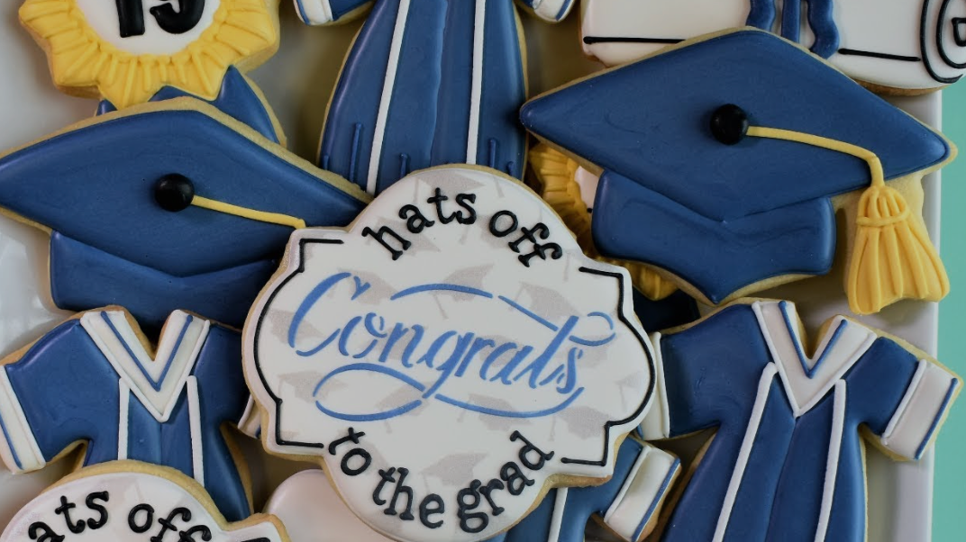 A platter of blue and yellow graduation-themed cookies, including mortarboards, gowns, and a