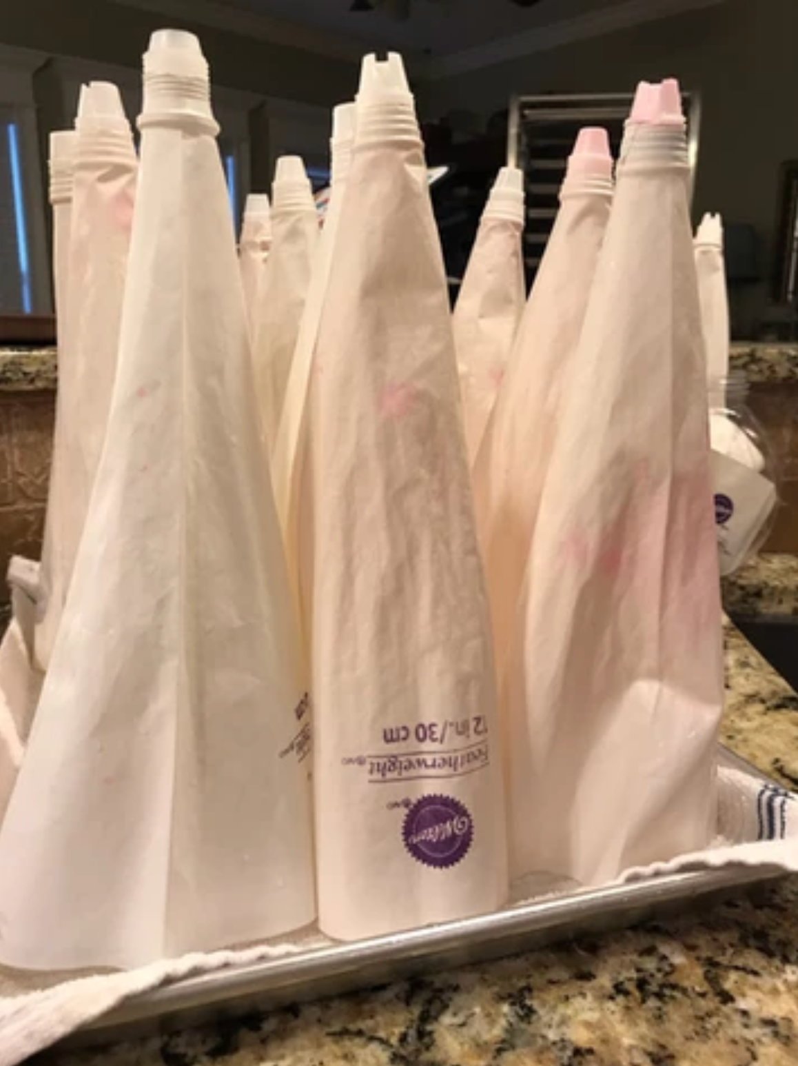 Piping bags filled with frosting, standing in a tray, likely ready for cake decorating.