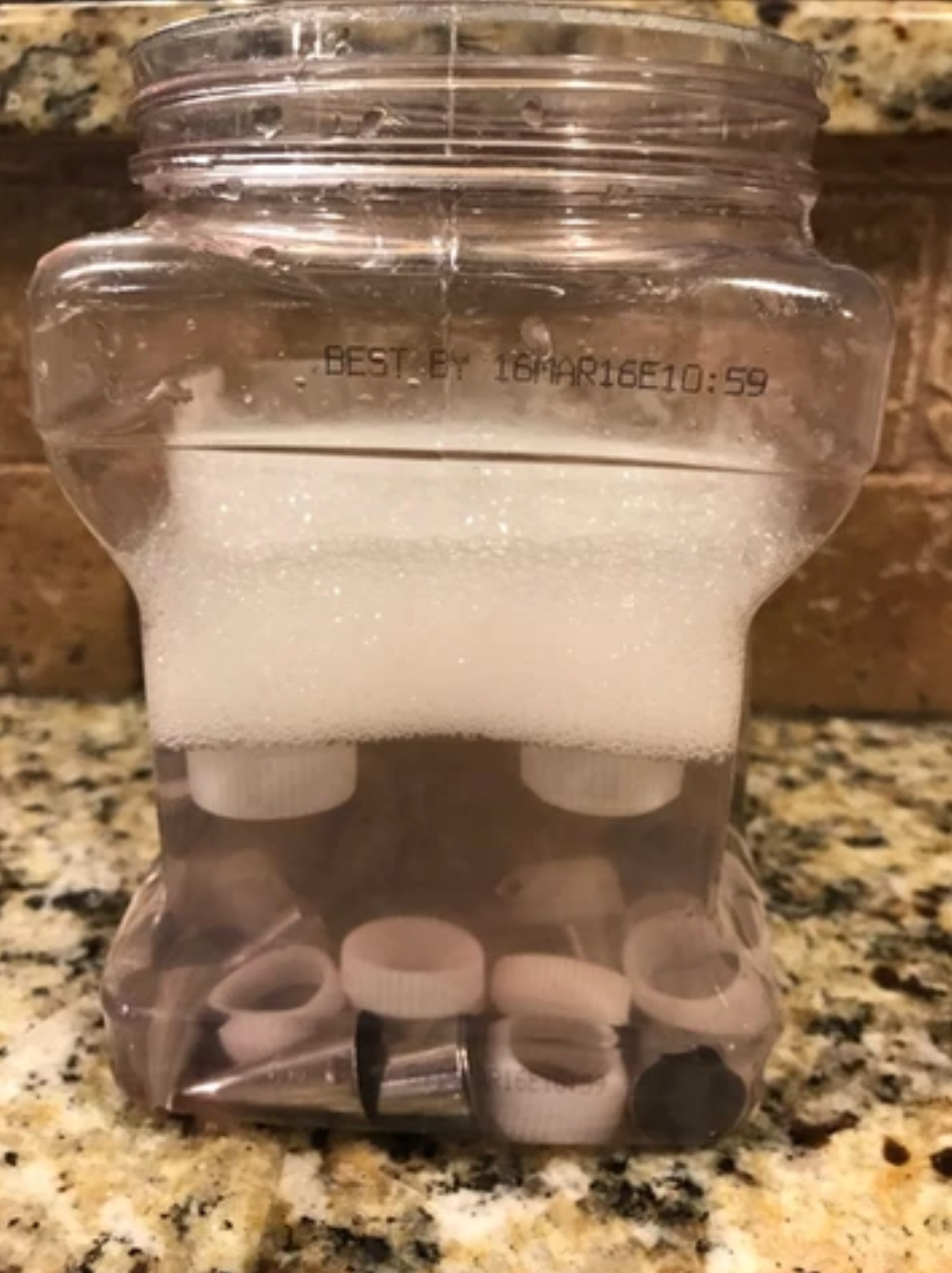 Clear plastic container with soapy water and small dental pieces.