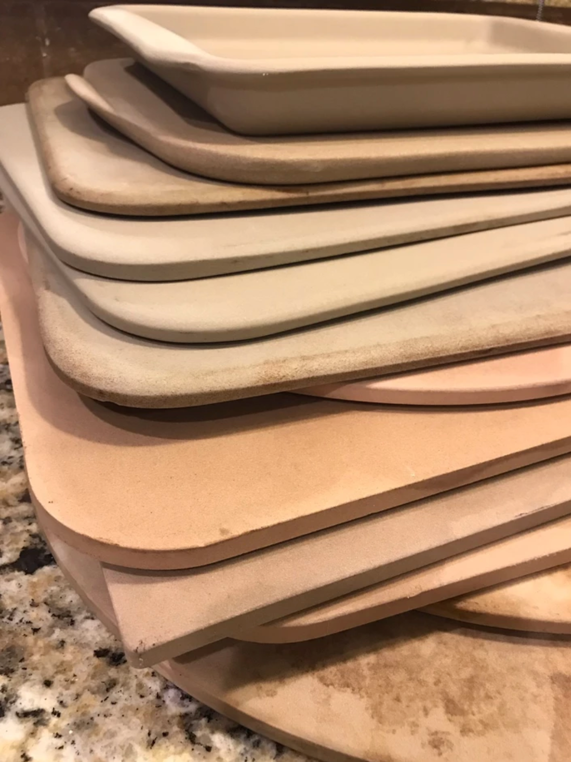 Pile of light brown stoneware baking items of various sizes.