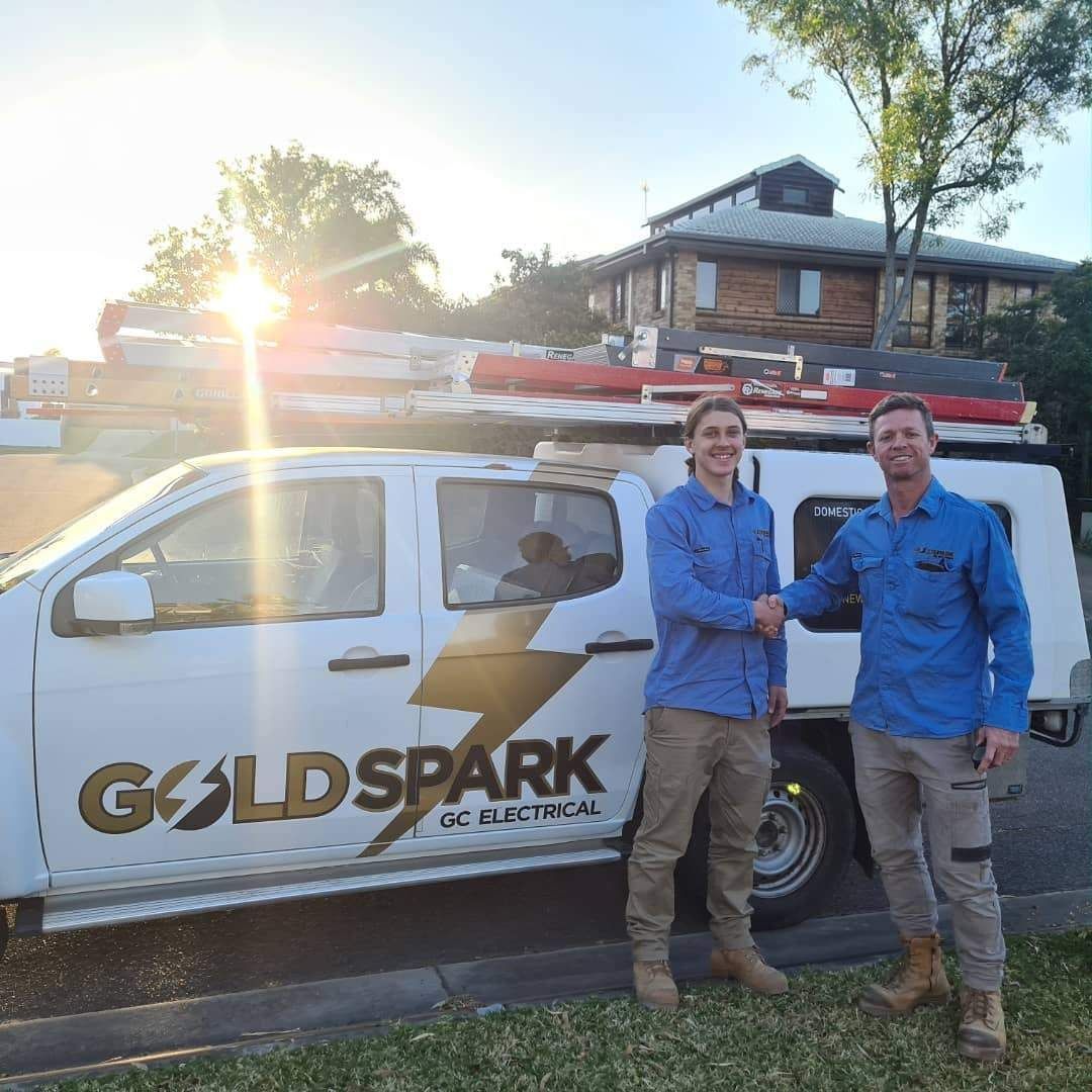 Two Men Are Shaking Hands in Front of A Goldspark Truck — Goldspark GC Electrical in Burleigh Waters, QLD