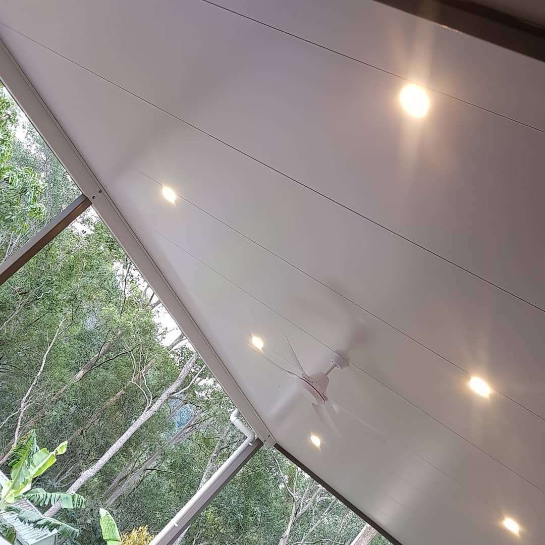 A Ceiling Fan Is Hanging from The Ceiling of A Room with Trees in The Background — Goldspark GC Electrical in Nerang, QLD