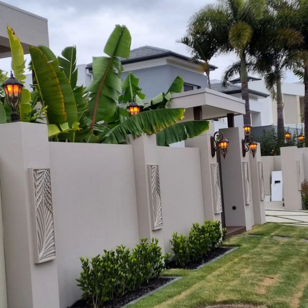 A Fence Surrounds a Lush Green Yard with Palm Trees — Goldspark GC Electrical in Southport, QLD
