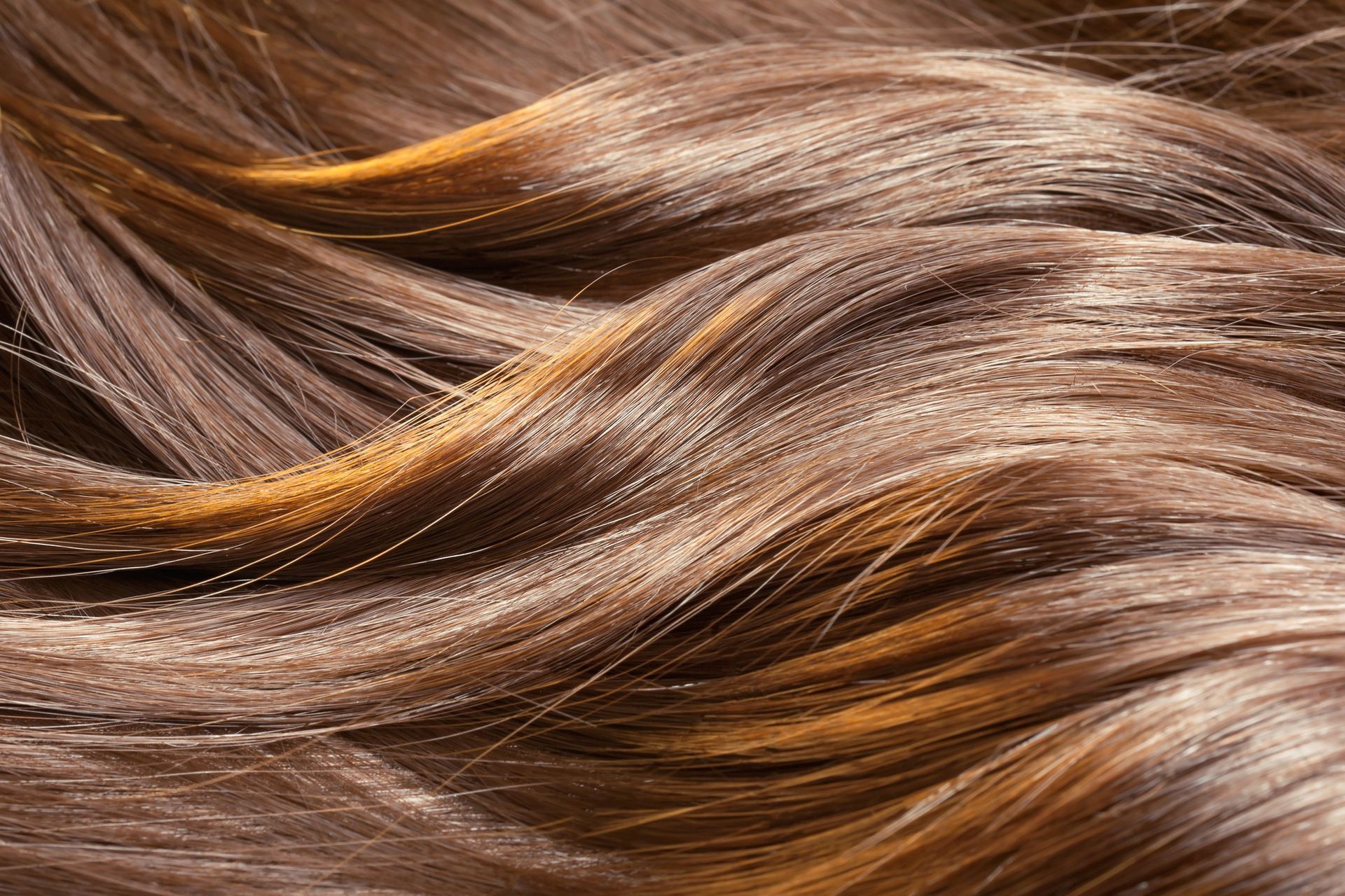 Primo piano di capelli castani ondulati con riflessi dorati