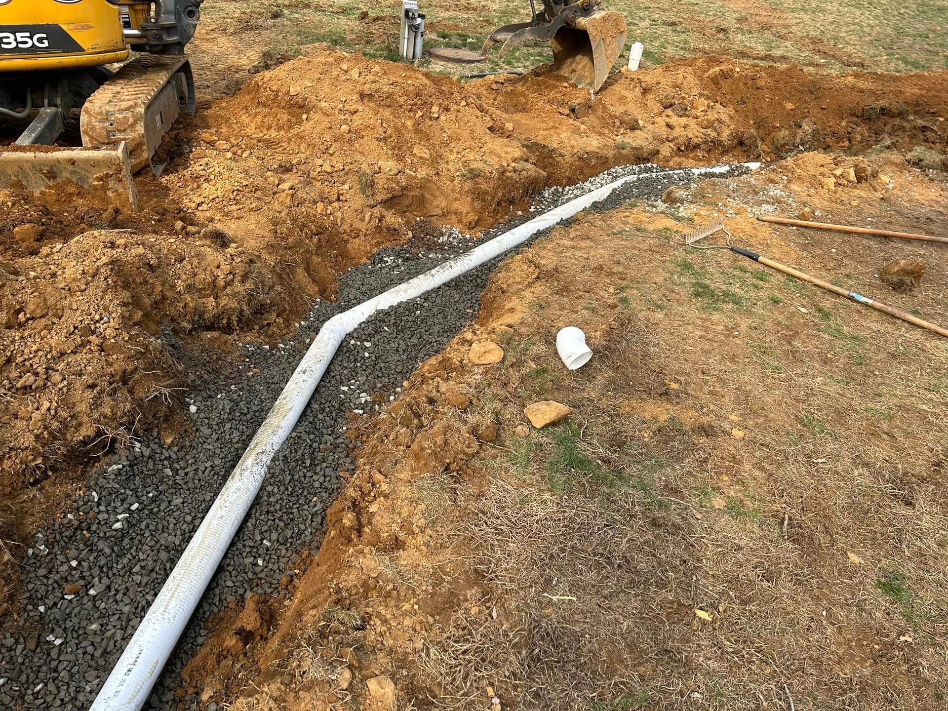 A pipe is being installed in the dirt next to a bulldozer.