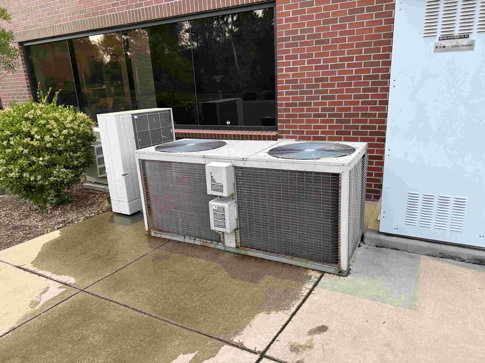 Large outdoor air conditioning unit next to a brick commercial building downtown Medford, Oregon.